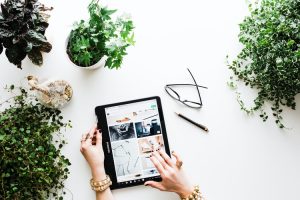 using colored-black tablet with ballpen , eyeglass ang plants in the table